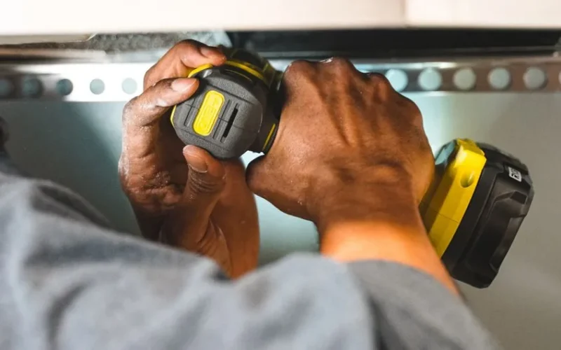 Close-up of worker's hands operating a power tool during a construction task.