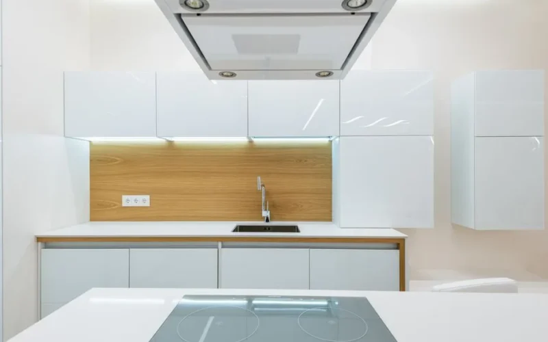 Interior of new empty kitchen with white furniture with wooden elements in modern apartment