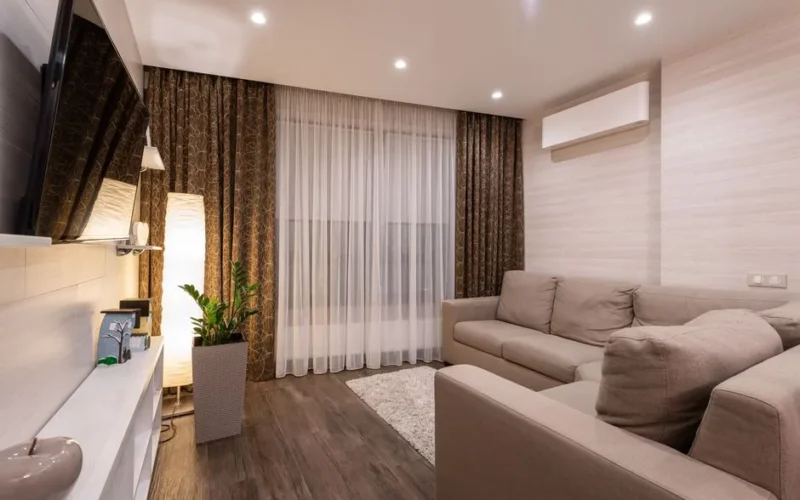 A stylish and cozy living room featuring a sofa, wooden flooring, and soft lighting.