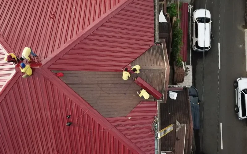 Aerial view of workers repairing a red metal roof in Quezon City, Philippines.
