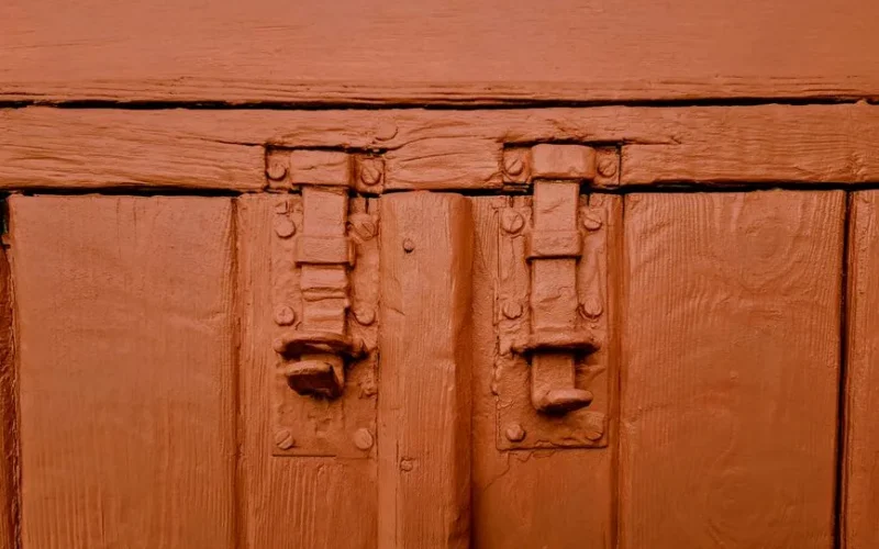 Close-up of a vintage red-painted wooden door with metal latches in Nicosia, Cyprus.