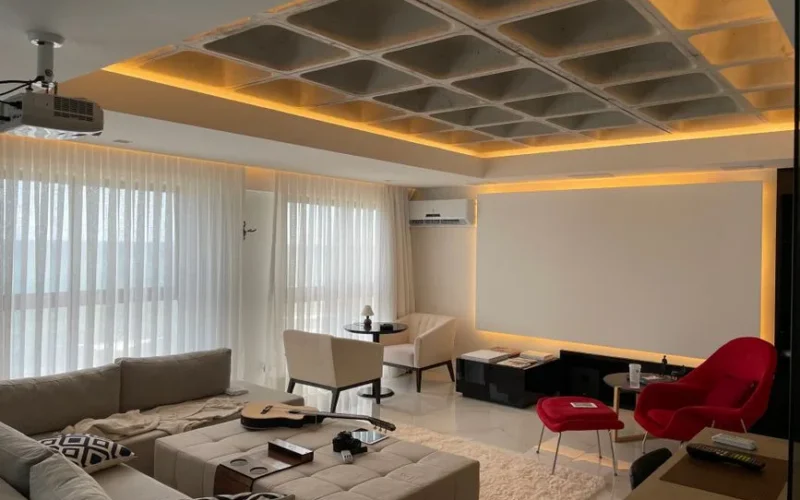 Spacious minimalist living room with natural light, featuring cozy seating and a ceiling projector.