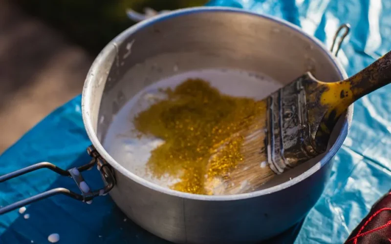 Close-up of a paintbrush and glitter in a pot, perfect for DIY projects.