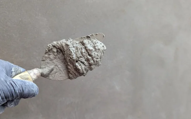 Close-up of a hand holding a trowel with cement, perfect for construction themes.