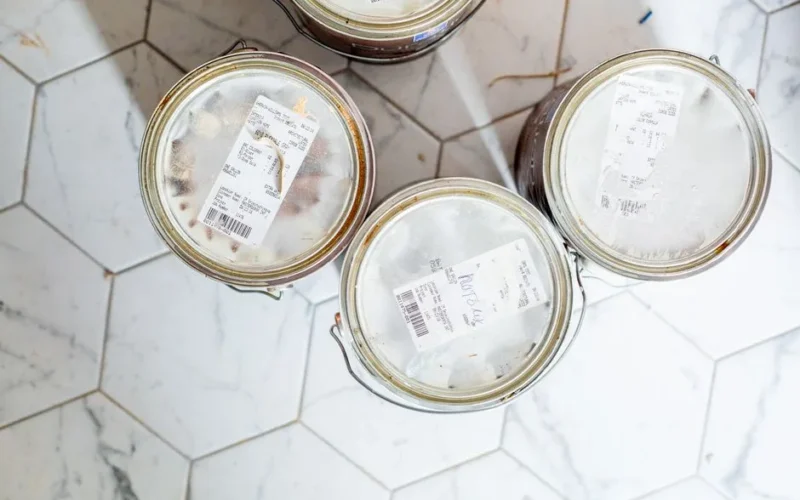 Top view of three paint cans on a hexagonal tile floor, ready for home renovation.