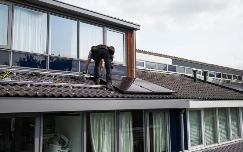 Technician working on installing solar panels on a residential rooftop during the day.