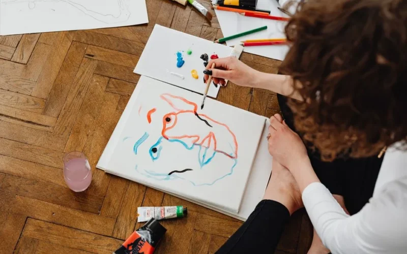 Artist painting abstract face on canvas with vibrant colors.