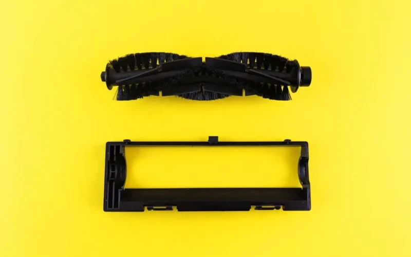 Close-up of vacuum cleaner components on vibrant yellow surface, highlighting maintenance and cleaning.