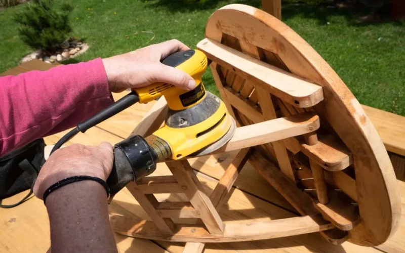 A person using a power sander on a wooden table outside in Boulder, Colorado.