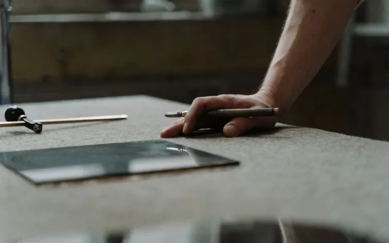 Hand of a craftsman working with a glass cutter in a professional workshop setting.