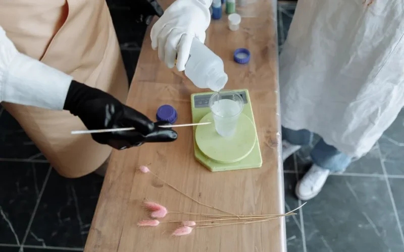 Detailed shot of mixing chemicals into a plastic cup using a measuring stick.