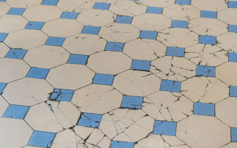 A detailed view of aged cracked tiles with a blue and white geometric pattern.