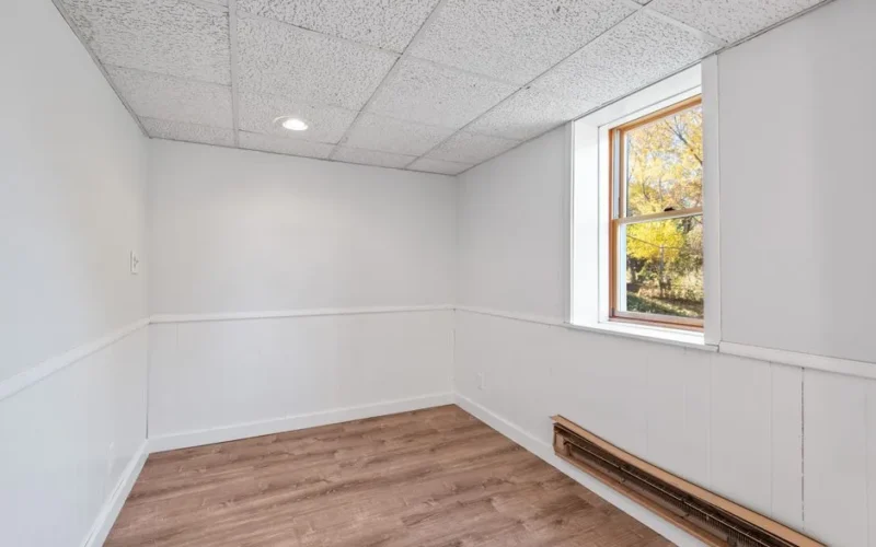 Bright empty room with wooden floor and window. Ideal for real estate or renovation projects.