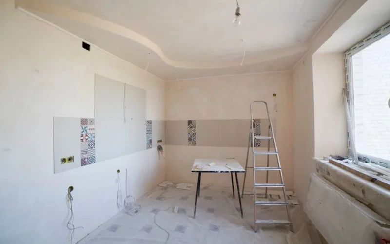 Spacious kitchen under renovation with ladder and tools, showcasing a fresh new design.
