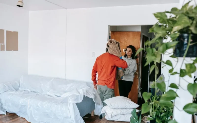 A couple arranging their new apartment, moving in furniture and household items.