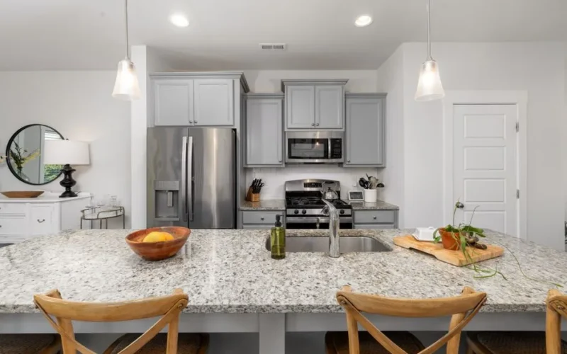 Sleek kitchen design featuring granite countertops, stainless steel appliances, and contemporary chairs.