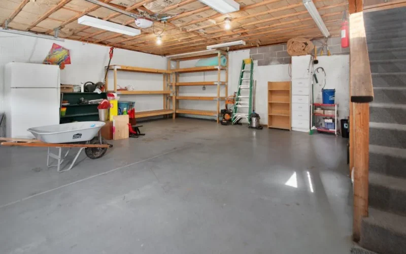 Spacious garage interior with storage shelves, tools, and a wheelbarrow, ideal for home organization.