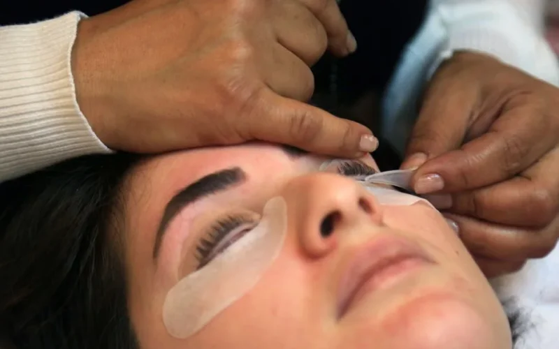 Close-up of a woman receiving an eyelash treatment in a spa setting, showcasing precision and care.