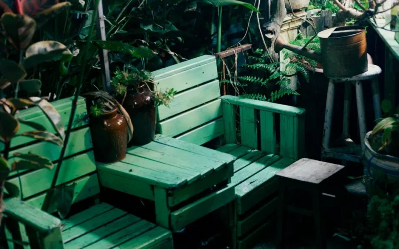 Charming outdoor garden seating area with green pallets and vintage watering can.