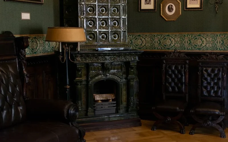 Classic room with a vintage tiled stove and leather furniture, exuding warmth and elegance.