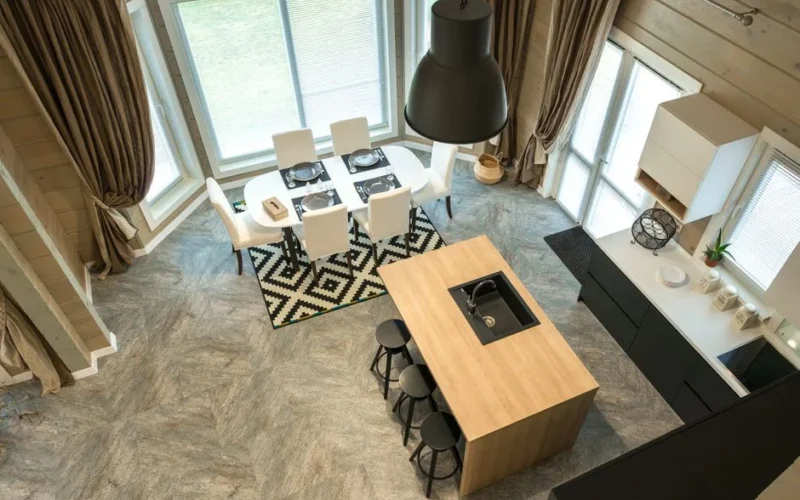 From above of stylish modern interior of kitchen with bar chairs at counter near served dining table