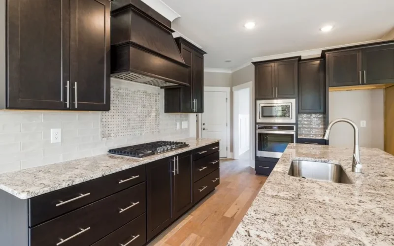 Contemporary kitchen featuring dark cabinetry, granite countertops, and stainless steel appliances.