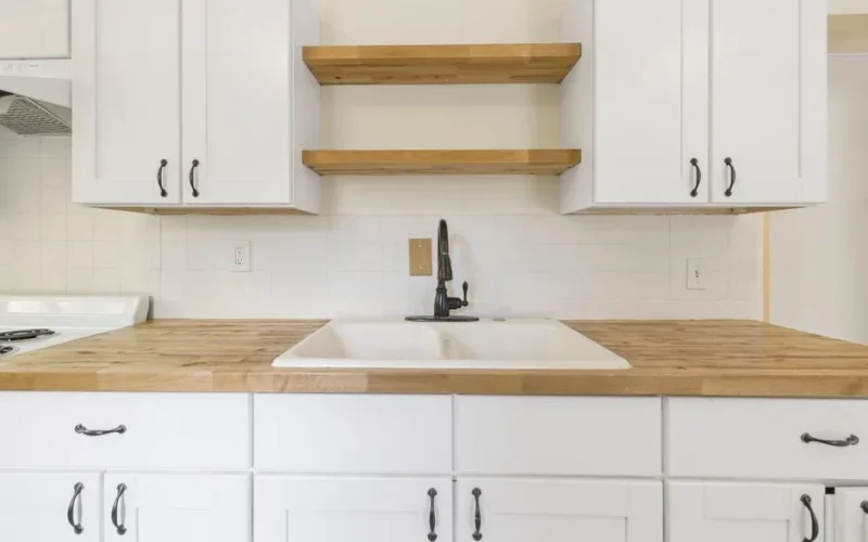 A spacious, modern kitchen with white cabinets and wood countertops.