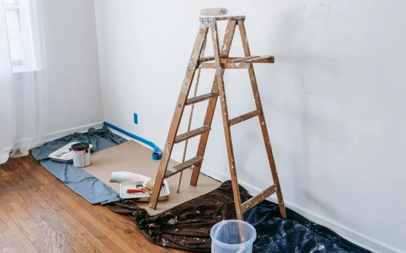 A room with a stepladder and painting tools, showcasing a renovation process.
