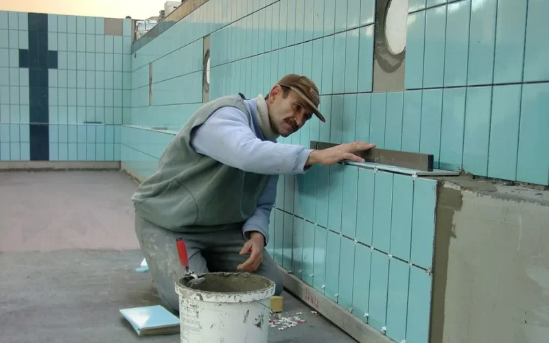 Tiler expertly aligns ceramic tiles on a swimming pool wall. Indoor construction setting in Wrocław.