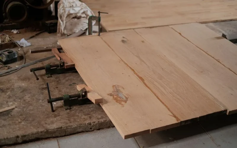 Detailed view of clamped wooden planks in a woodworking workshop.