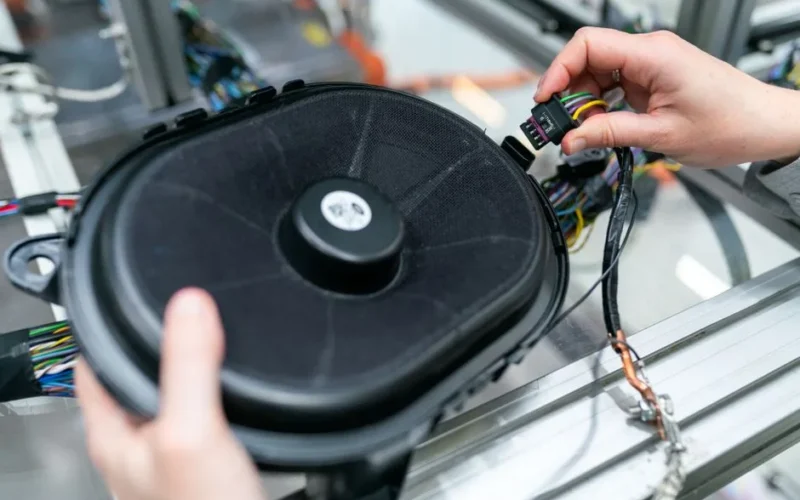 Close-up of an engineer working on a sound system speaker assembly in a workshop.