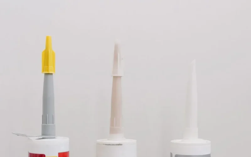 Set of various plastic tubes with glue for renovation works in workshop against white background