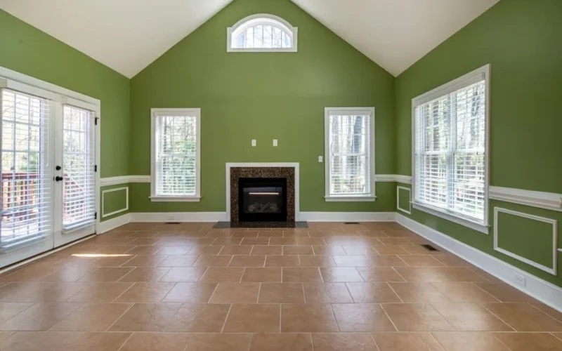 Elegant empty living room featuring green walls, a fireplace, and tiled flooring.