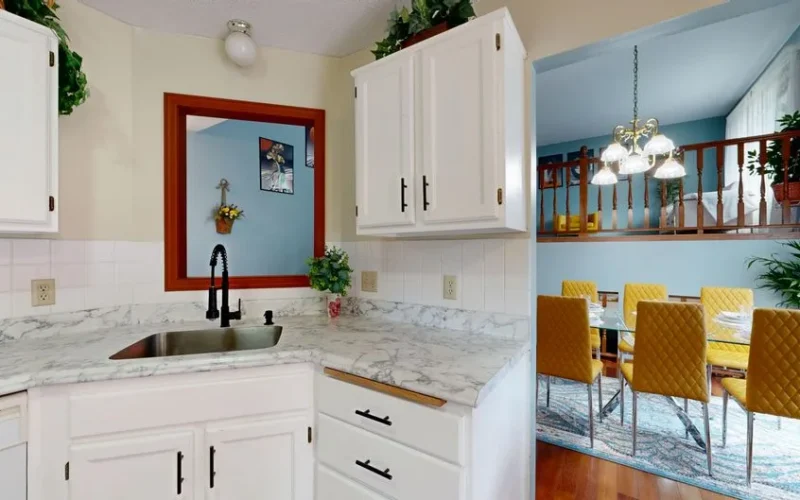 Bright modern kitchen with marble countertops overlooking a stylish dining area.