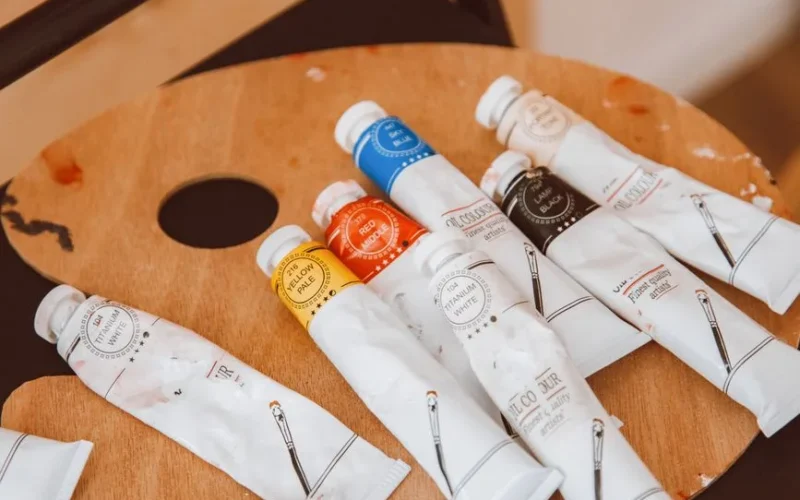 Artistic close-up of vibrant paint tubes on a wooden palette in an art studio.