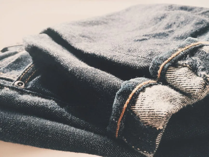 Detailed view of folded denim jeans in soft, warm lighting.