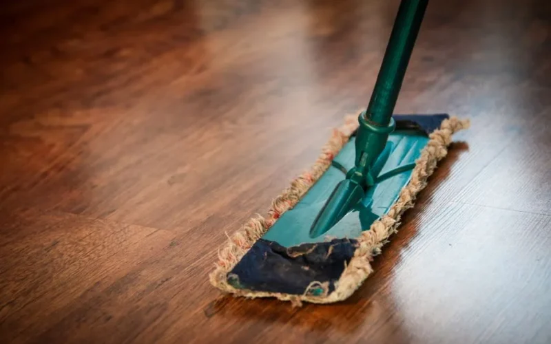 A detailed view of a mop cleaning a wooden floor, showing texture and pattern.