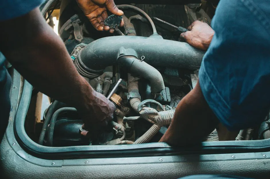 Auto mechanics repairing an engine in a Nigerian workshop. Close-up hands and tools.