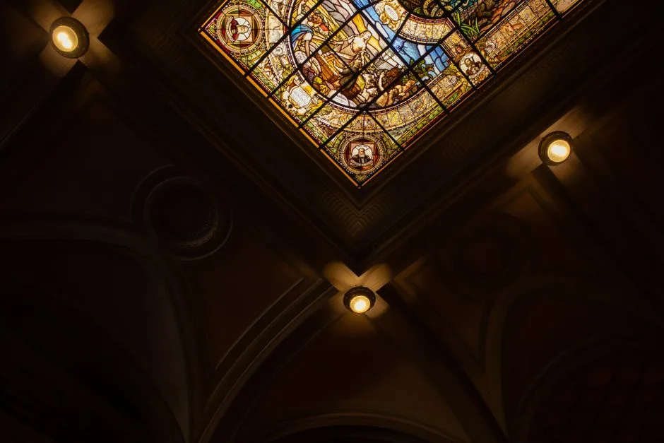 Decorative stained glass ceiling in a dimly lit church interior.