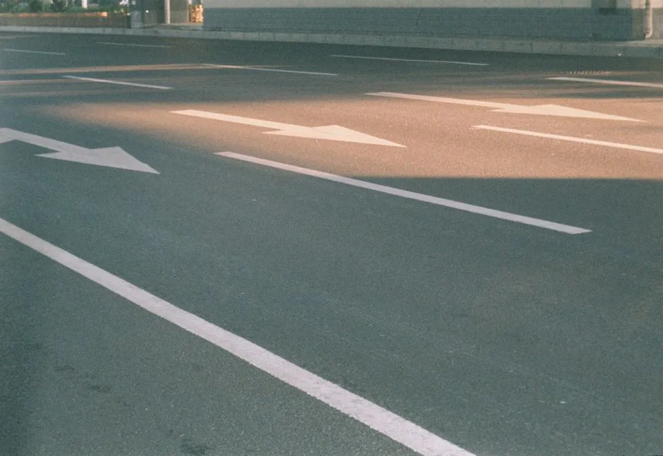 Photograph of a city street showing directional arrows on asphalt in sunlight.