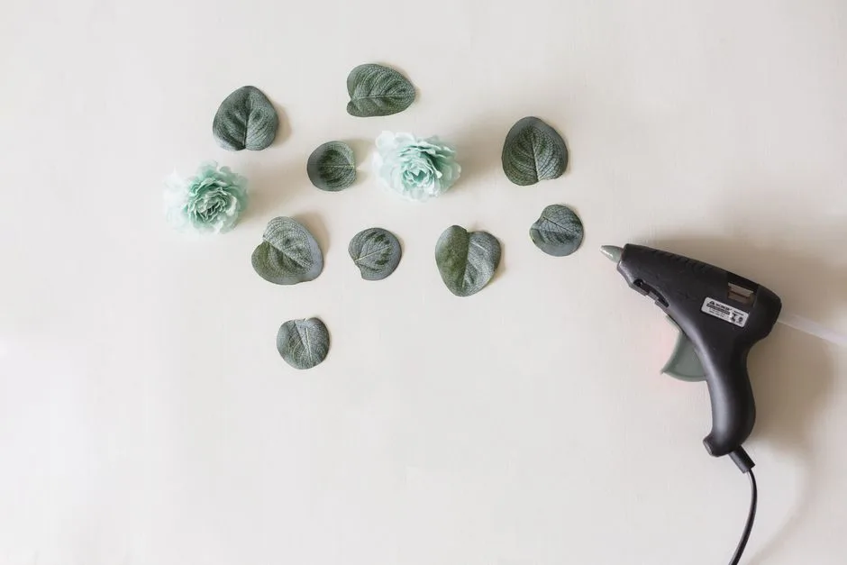 Arrangement of artificial flowers and leaves with a glue gun, perfect for DIY crafts.
