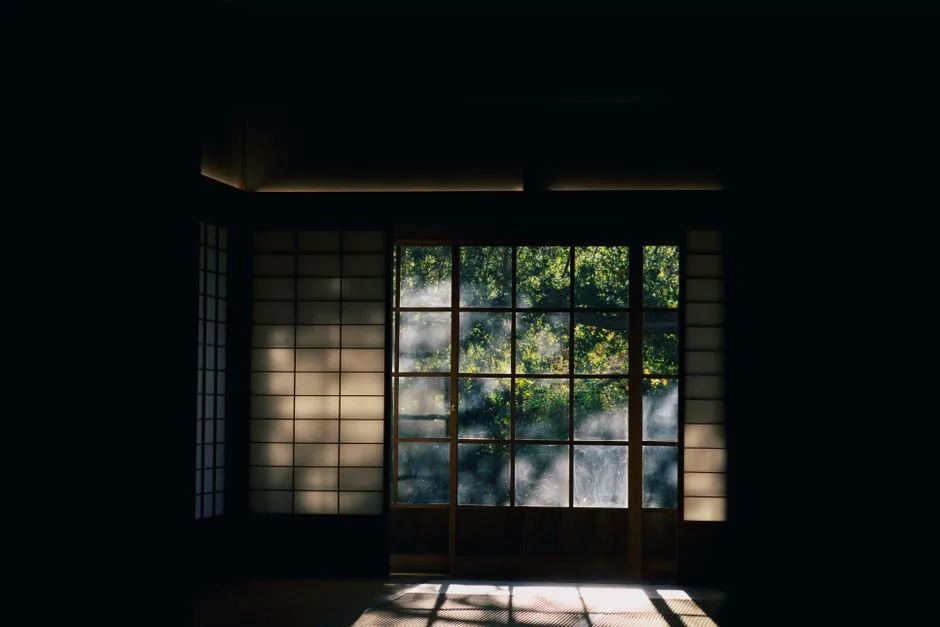 Serene Japanese interior with shoji doors framing a lush green garden view, conveying peace and tranquility.