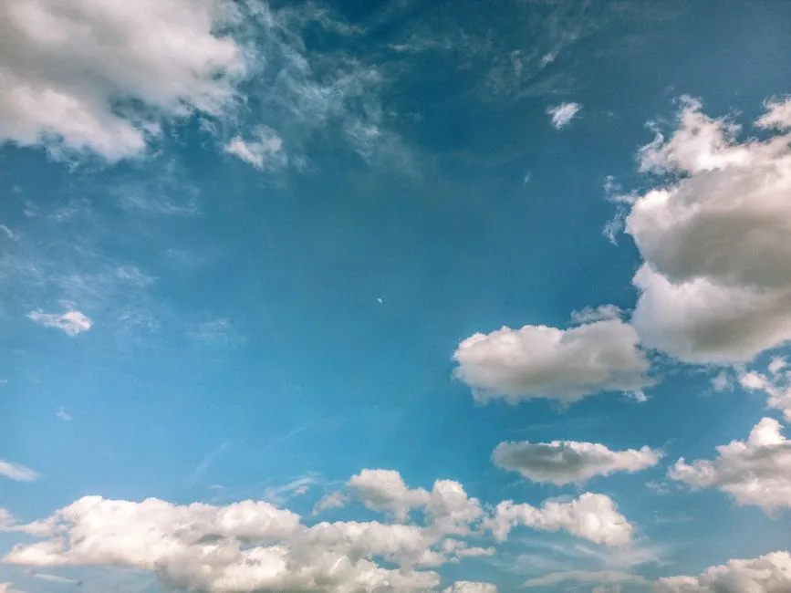 A clear blue sky filled with scattered fluffy white clouds on a sunny day.