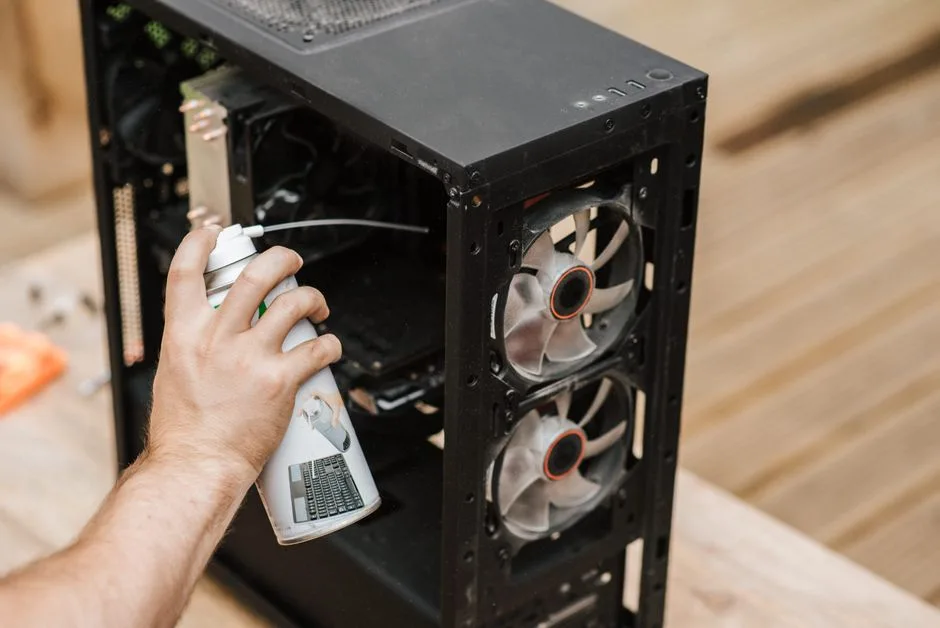 Crop anonymous male with compressed air can removing dust from computer system unit
