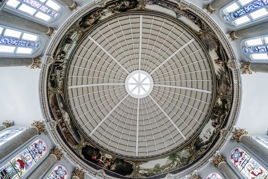 A top-down view of an ornate church ceiling with a painted dome and stained glass windows.
