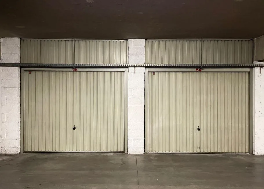 Two closed garage doors inside an empty warehouse space.