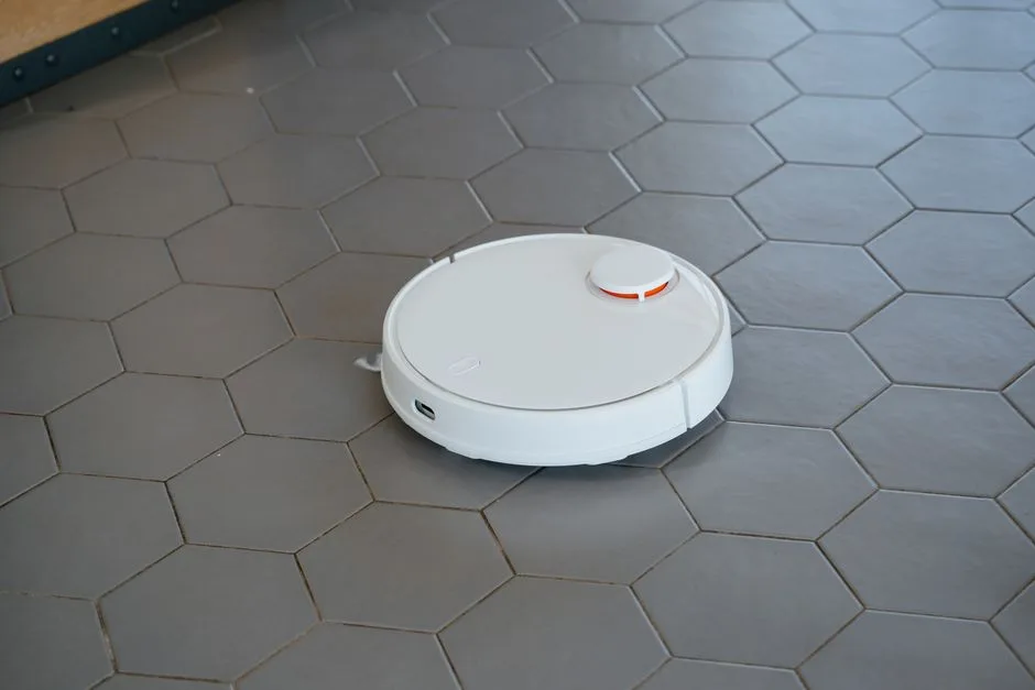 A sleek, white robotic vacuum cleaner operating on a hexagonal tiled floor.
