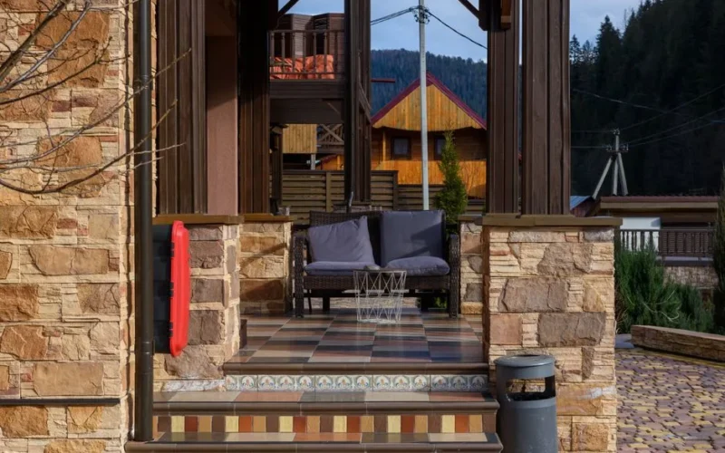 Charming mountain chalet with a tiled porch, accented with stone and wood elements.
