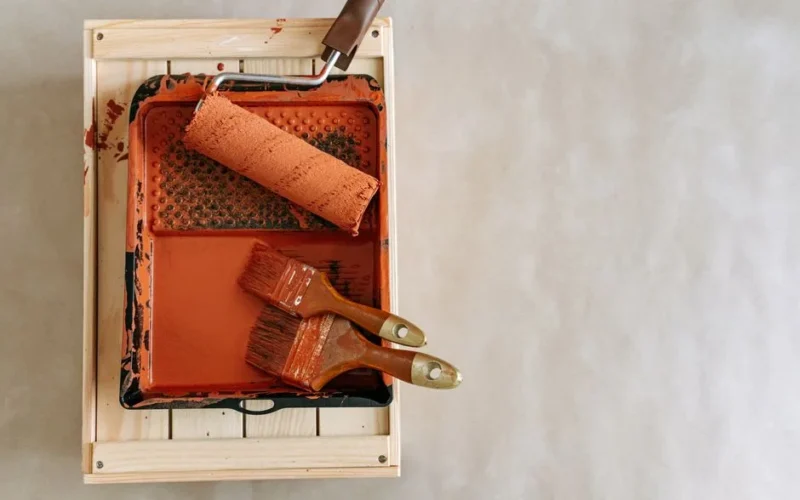 An overhead shot of paintbrushes and a roller in a tray, perfect for home renovation projects.