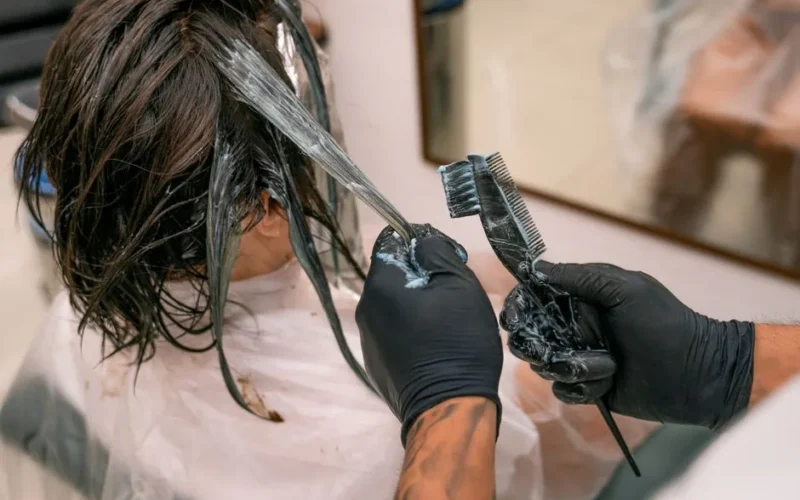 Close-up of hair coloring process in a salon. Hairdresser applying dye to client's hair.